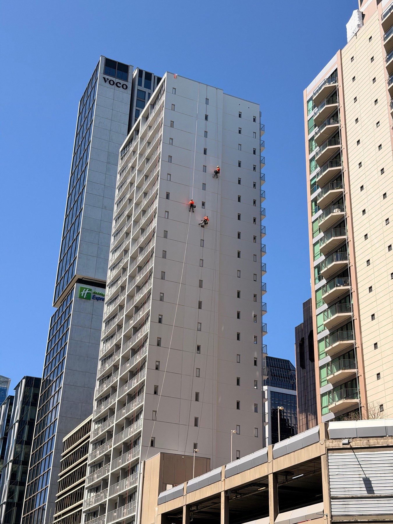Two On Ropes technicians on a full-height drop down an Auckland apartment tower