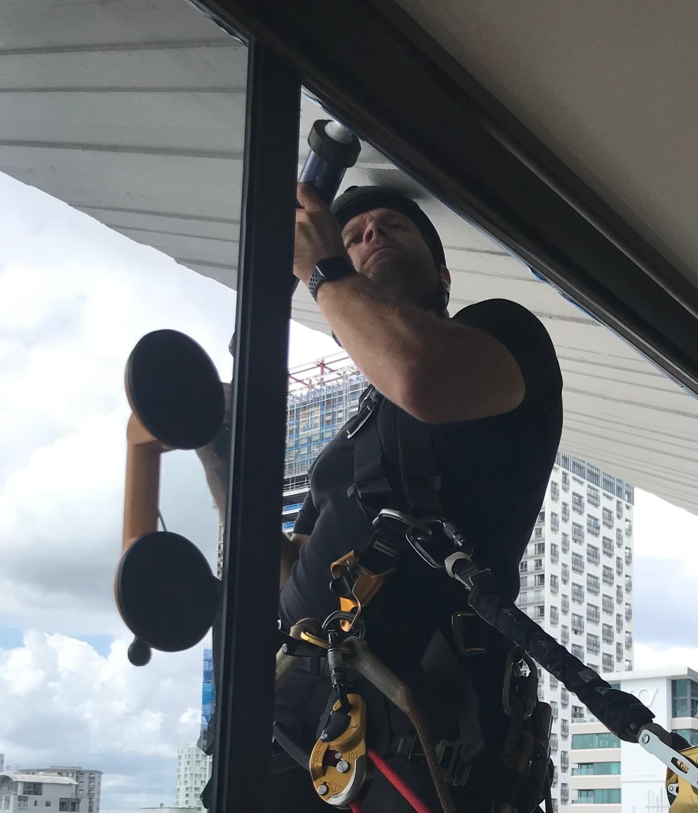 On Ropes technician checking a soffit junction with a torch from the rope