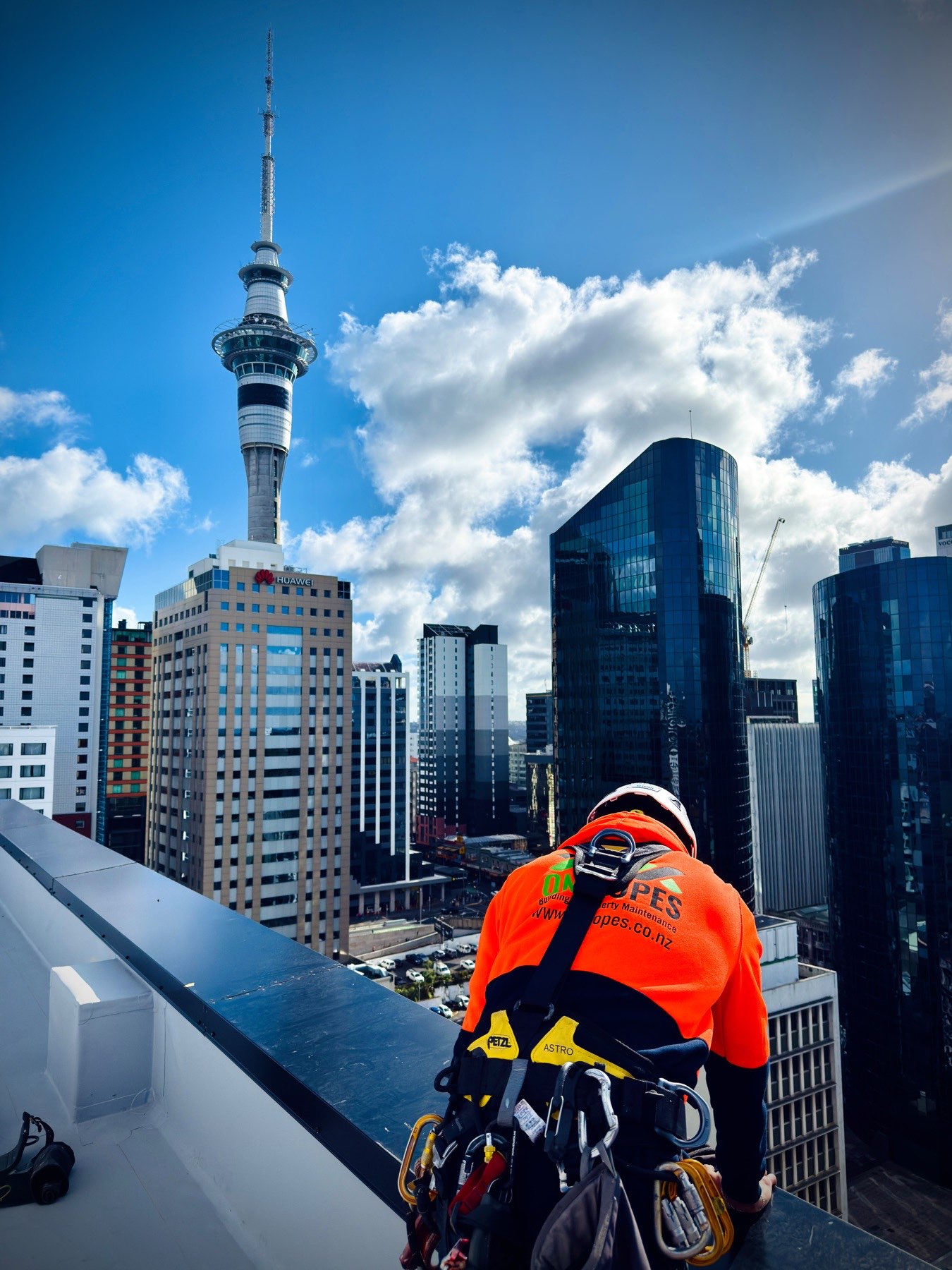 On Ropes technician rigging at an Auckland CBD parapet, Sky Tower behind