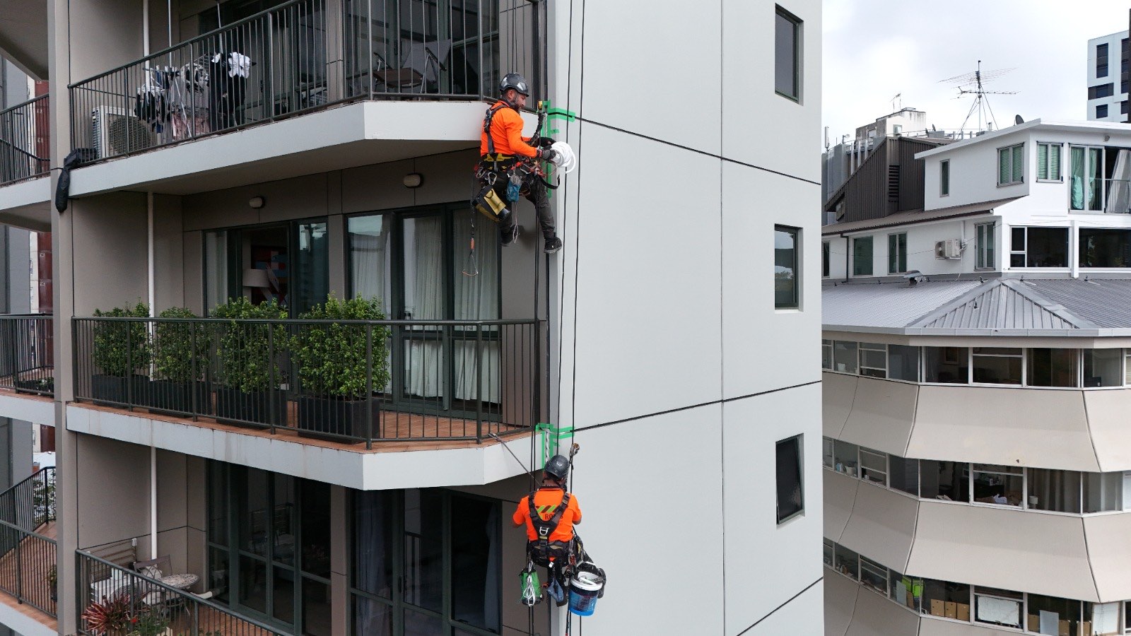 Two On Ropes technicians resealing a vertical control joint from ropes