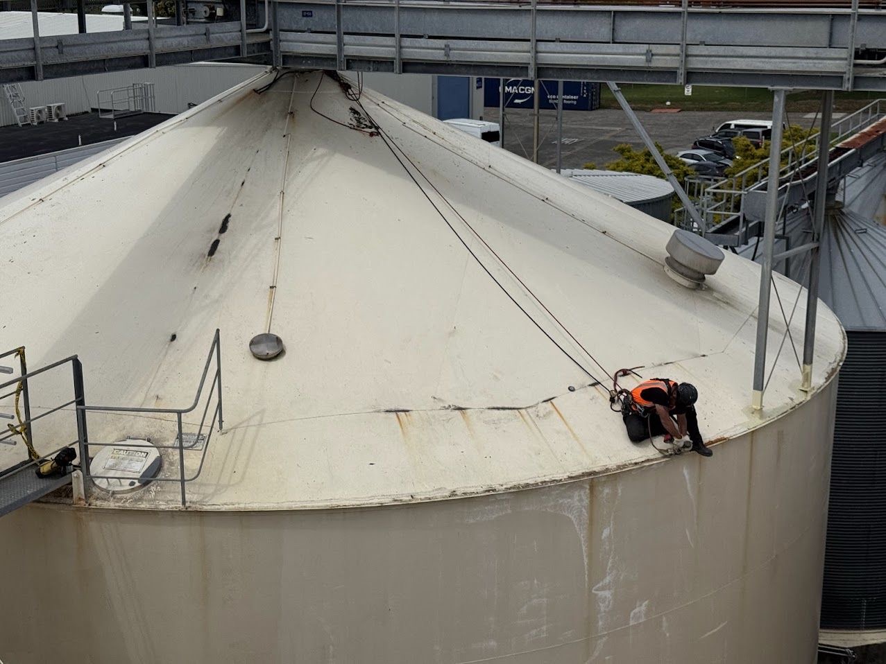 On Ropes technician working the edge of a silo roof on rope at an industrial site