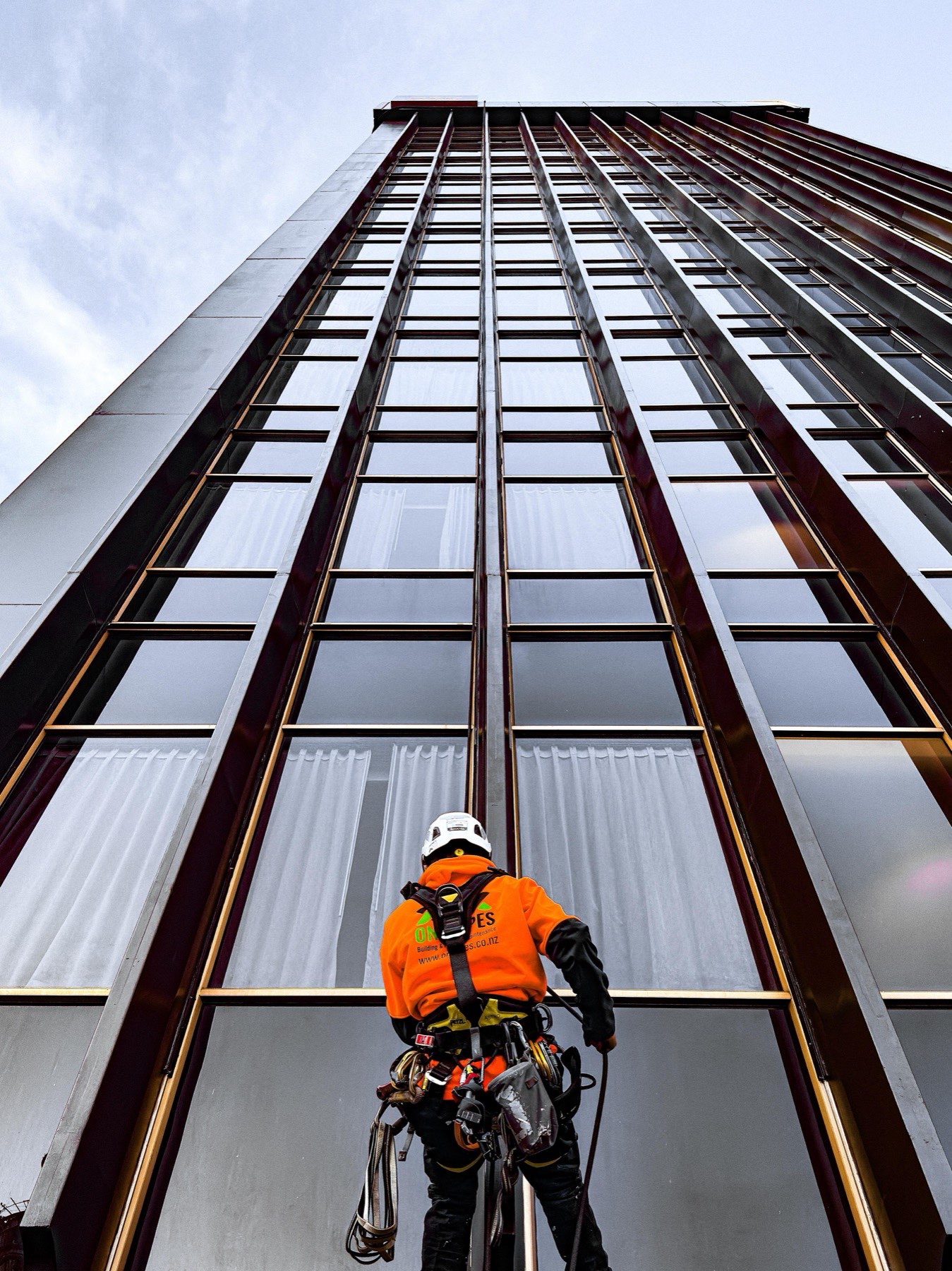 Glazed tower elevation seen from below with a technician rigged at its base